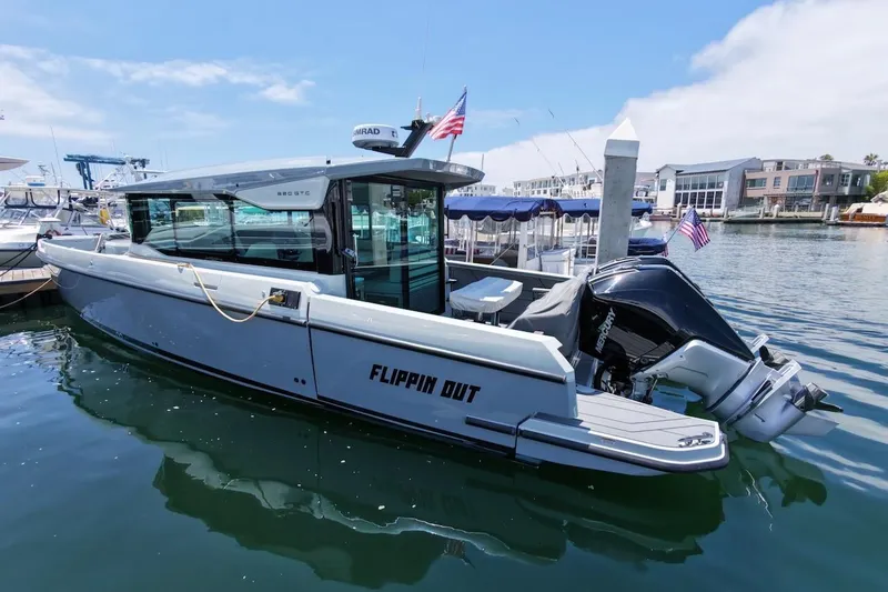Slide: The Image of 2024 Saxdor 320 GTC boat docked in marina, featuring sleek design and powerful outboard motor. - 2