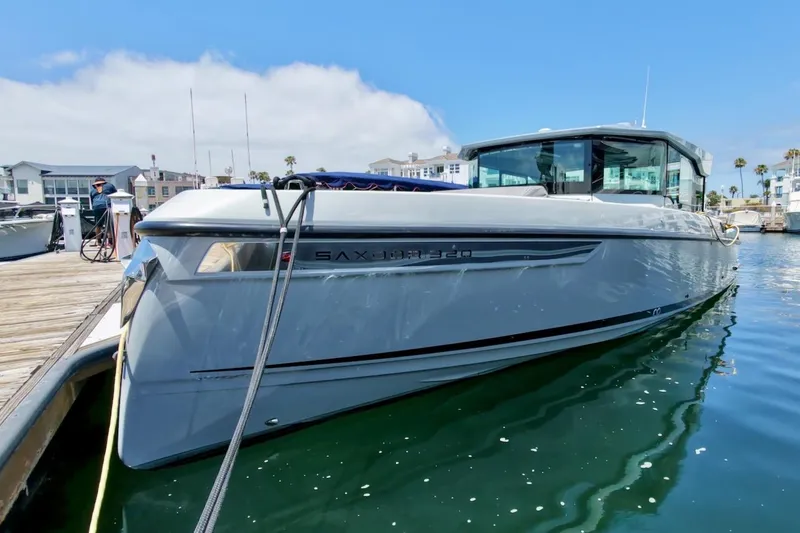 Slide: The Image of 2024 Saxdor 320 GTC boat docked at marina under clear blue sky. - 1