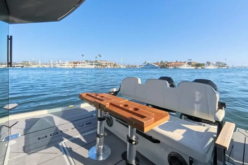 Slide: The Image of 2024 Saxdor 320 GTC boat interior with seating and table, overlooking a scenic waterfront. - 11
