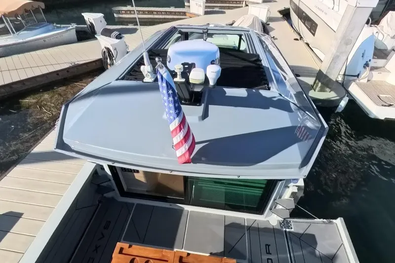 Slide: The Image of 2024 Saxdor 320 GTC boat docked, featuring sleek design and American flag on deck. - 50