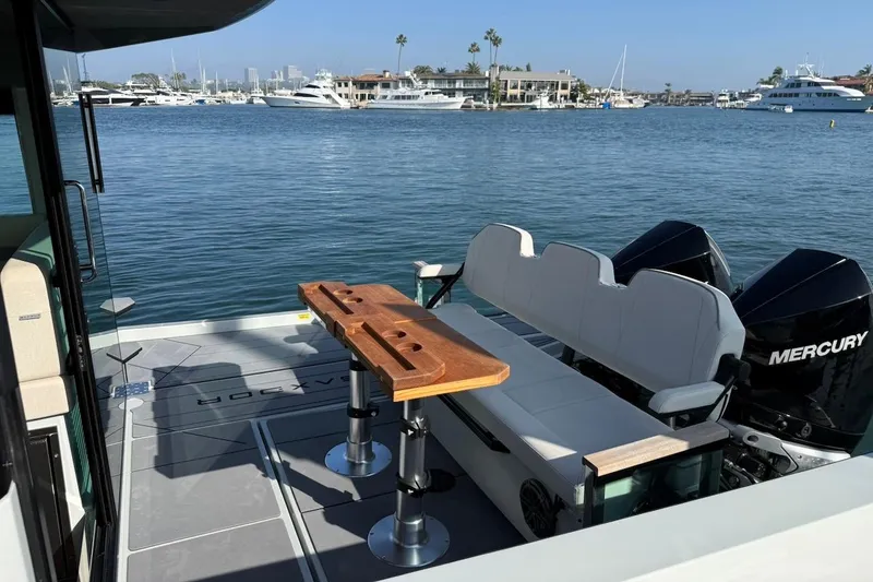 Slide: The Image of 2024 Saxdor 320 GTC boat interior with seating, table, and Mercury engines on a sunny day. - 10