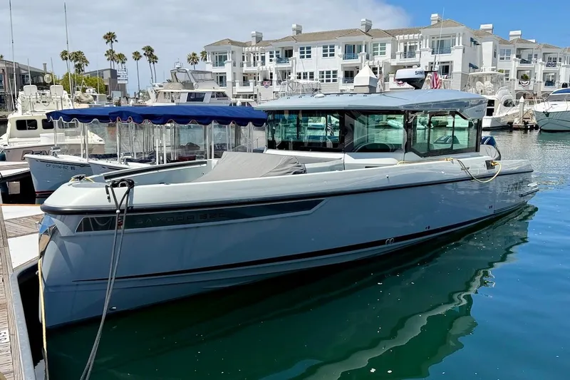 The Image of 2024 Saxdor 320 GTC boat docked in a marina with waterfront buildings. - 0
