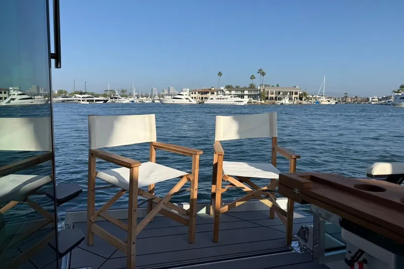 Slide: The Image of Two chairs on Saxdor 320 GTC yacht deck overlooking marina, 2024 model. - 12