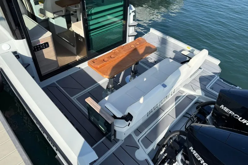 Slide: The Image of 2024 Saxdor 320 GTC boat with seating area, wooden table, and dual Mercury engines. - 7