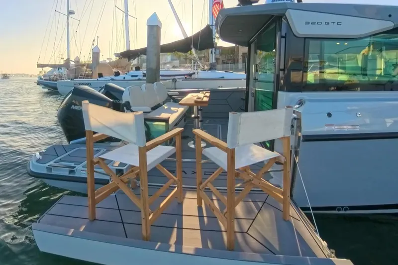 Slide: The Image of 2024 Saxdor 320 GTC boat with deck chairs, docked in a marina at sunset. - 13