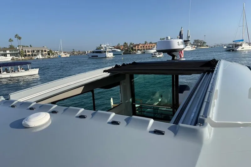 Slide: The Image of 2024 Saxdor 320 GTC yacht with open sunroof, cruising in a scenic harbor. - 47