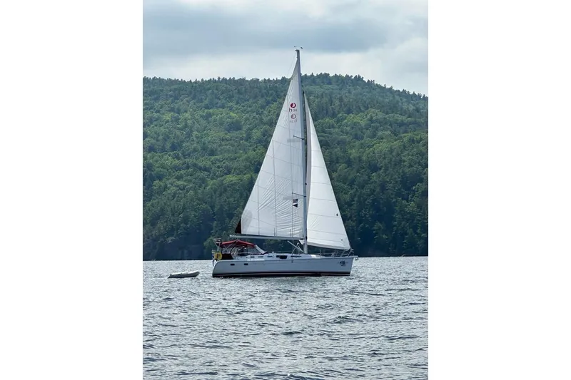 Slide: The Image of Sailboat Hunter 38 (2005) cruising on a lake with forested hills in the background. - 3