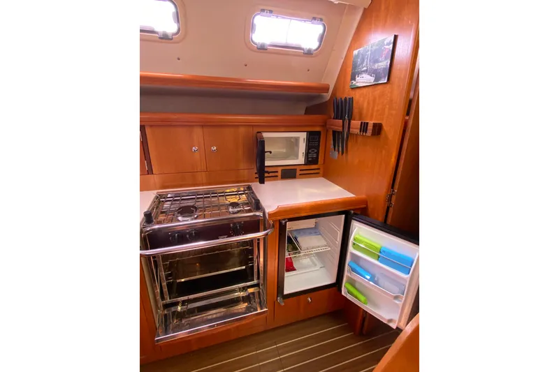 Slide: The Image of Compact kitchen in a 2005 Hunter 38 sailboat with stove, microwave, and fridge. - 18