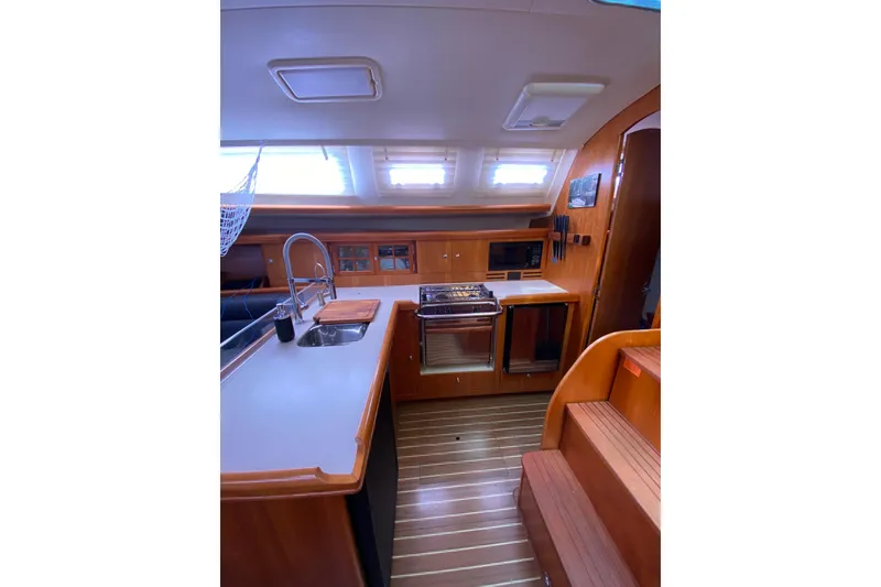 Slide: The Image of Interior of 2005 Hunter 38 sailboat featuring a modern kitchen with wood finishes. - 16