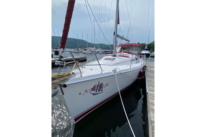 Slide: The Image of 2005 Hunter 38 sailboat docked at marina with red accents and clear sky. - 2