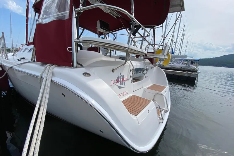 Slide: The Image of 2005 Hunter 38 sailboat docked, featuring red canopy and sleek white hull. - 9