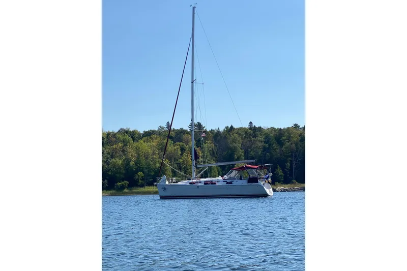 Slide: The Image of Sailboat on calm water, 2005 Hunter 38 model, with forested shoreline in the background. - 4