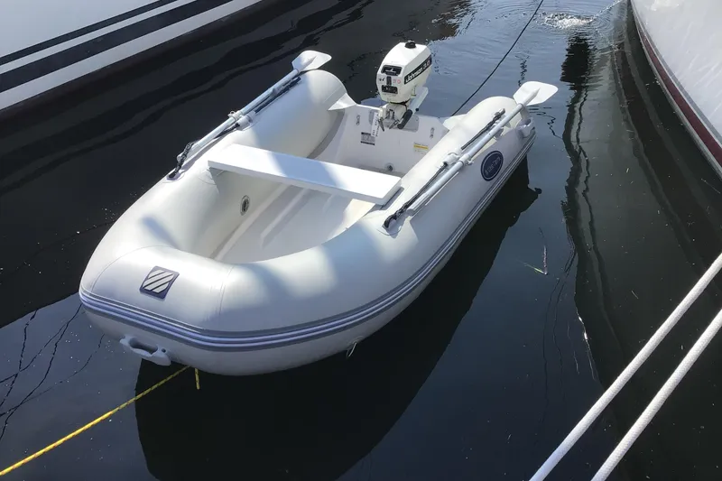 Slide: The Image of White inflatable boat with outboard motor, docked on calm water. Hunter 38, 2005 model. - 32