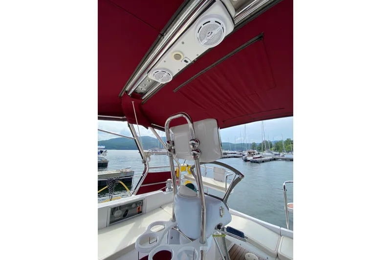 Slide: The Image of Interior view of a 2005 Hunter 38 sailboat cockpit with red canopy and marina background. - 7