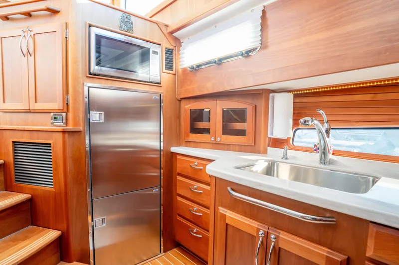 Slide: The Image of Luxurious 2016 Sabre 48 Salon Express yacht kitchen with stainless steel appliances and wooden cabinetry. - 28