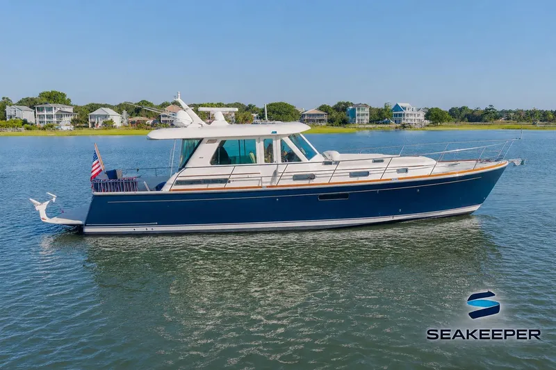The Image of 2016 Sabre 48 Salon Express yacht on calm water, with coastal homes in the background. - 0