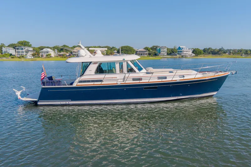 The Image of 2016 Sabre 48 Salon Express yacht on calm water, with coastal homes in the background. - 1