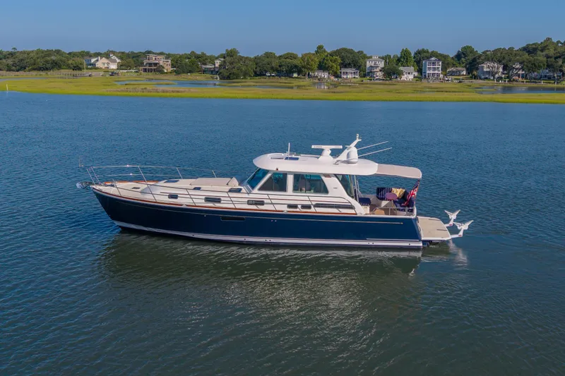 Slide: The Image of 2016 Sabre 48 Salon Express yacht cruising on a serene lake with scenic shoreline. - 2