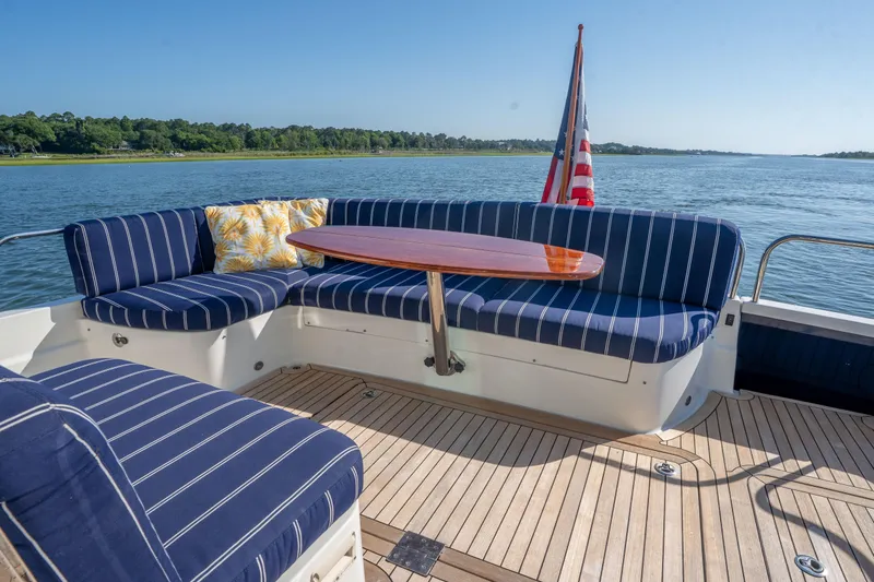 Slide: The Image of 2016 Sabre 48 Salon Express yacht with striped seating, wooden table, and scenic water view. - 8