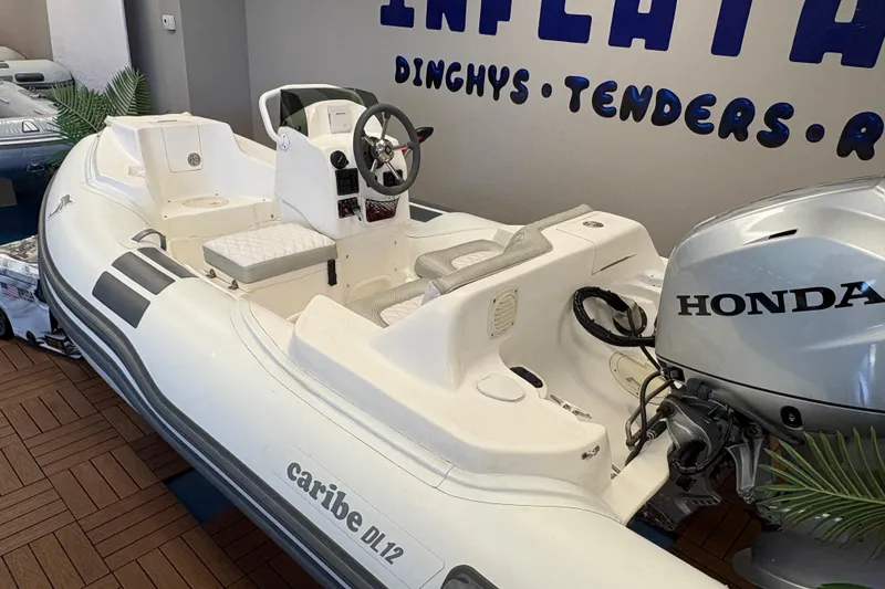 Slide: The Image of 2019 Caribe DL12 inflatable boat with Honda outboard motor displayed indoors. - 4