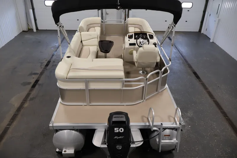 Slide: The Image of 2013 Bennington 20 SLMX pontoon boat with beige seating and black canopy in a garage. - 9