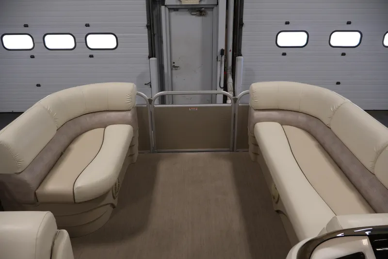 Slide: The Image of 2013 Bennington 20 SLMX pontoon boat interior with beige seating in a garage setting. - 10