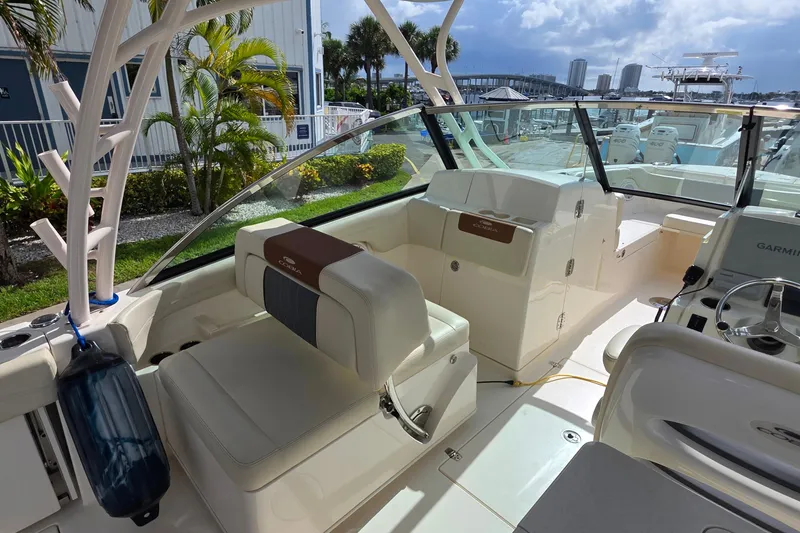 Slide: The Image of 2019 Cobia 280 Dual Console boat interior with seating and steering wheel, docked near marina. - 19