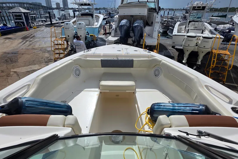 Slide: The Image of 2019 Cobia 280 Dual Console boat interior at marina, showcasing seating and equipment. - 16