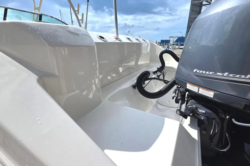 Slide: The Image of 2019 Cobia 280 Dual Console boat with four-stroke engine, docked under a clear sky. - 26