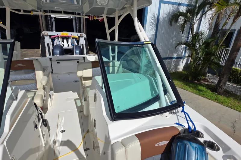 Slide: The Image of 2019 Cobia 280 Dual Console boat interior with seating and windshield, parked near a building. - 11