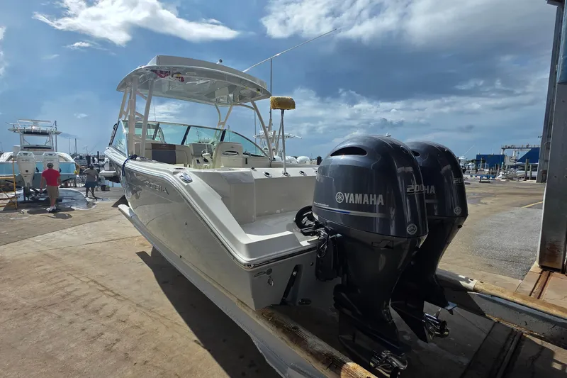 Slide: The Image of 2019 Cobia 280 Dual Console boat with twin Yamaha engines at a marina. - 27