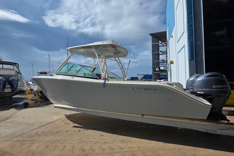 Slide: The Image of 2019 Cobia 280 Dual Console boat with Yamaha engines in a marina setting. - 4