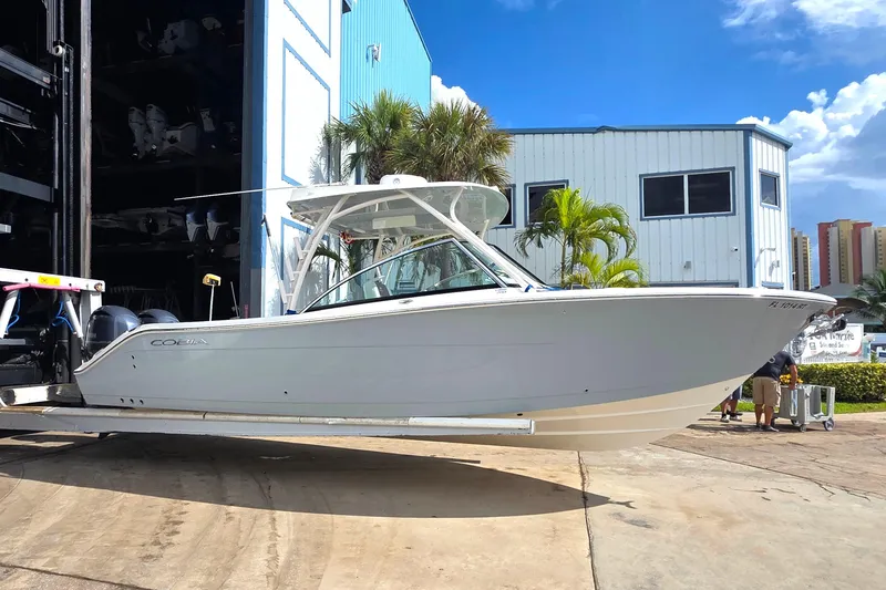 The Image of 2019 Cobia 280 Dual Console boat on trailer near marina building. - 0