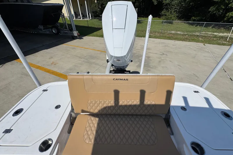 Slide: The Image of 2027 Caymas 26 HB boat with tan seating and outboard motor in a driveway. - 41