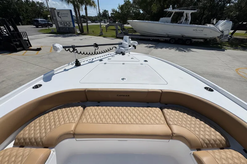 Slide: The Image of 2027 Caymas 26 HB boat with tan seating and trolling motor, parked outdoors. - 20