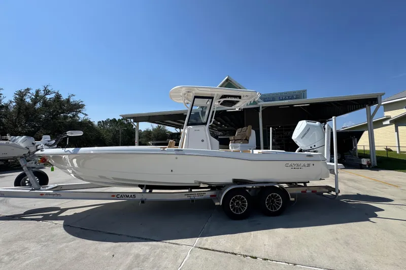 The Image of 2027 Caymas 26 HB boat on trailer, parked outdoors under clear blue sky. - 1