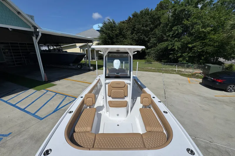 Slide: The Image of 2027 Caymas 26 HB boat with tan seating, parked outdoors on a sunny day. - 24