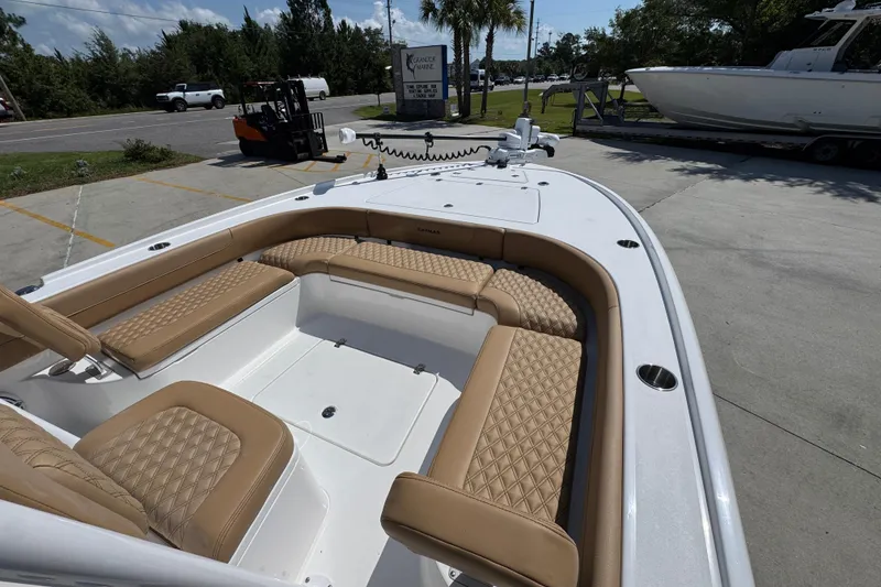 Slide: The Image of 2027 Caymas 26 HB boat with tan cushioned seating, parked outdoors. - 19