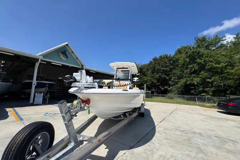 Slide: The Image of 2027 Caymas 26 HB boat on trailer outside a showroom under clear blue sky. - 5