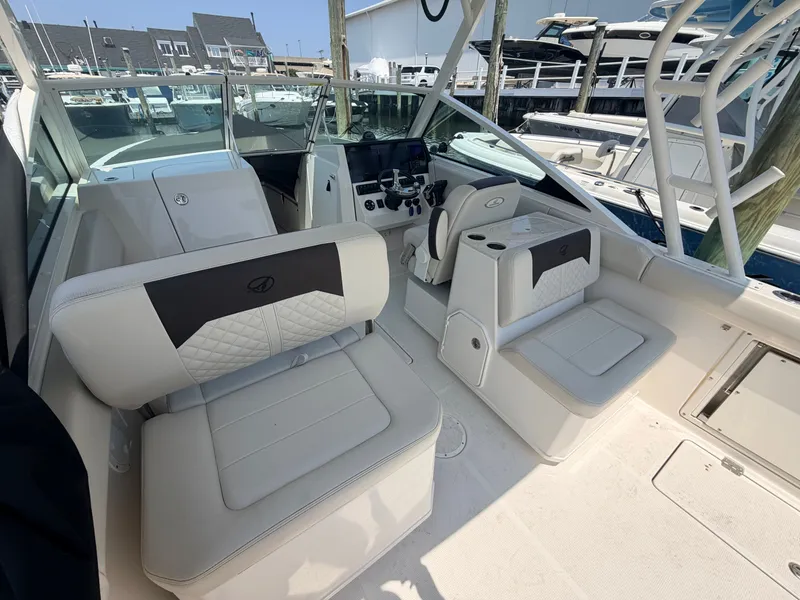 Slide: The Image of The image shows the cockpit of a 2022 Sailfish 276 DC boat with white cushioned seats and a helm. - 18