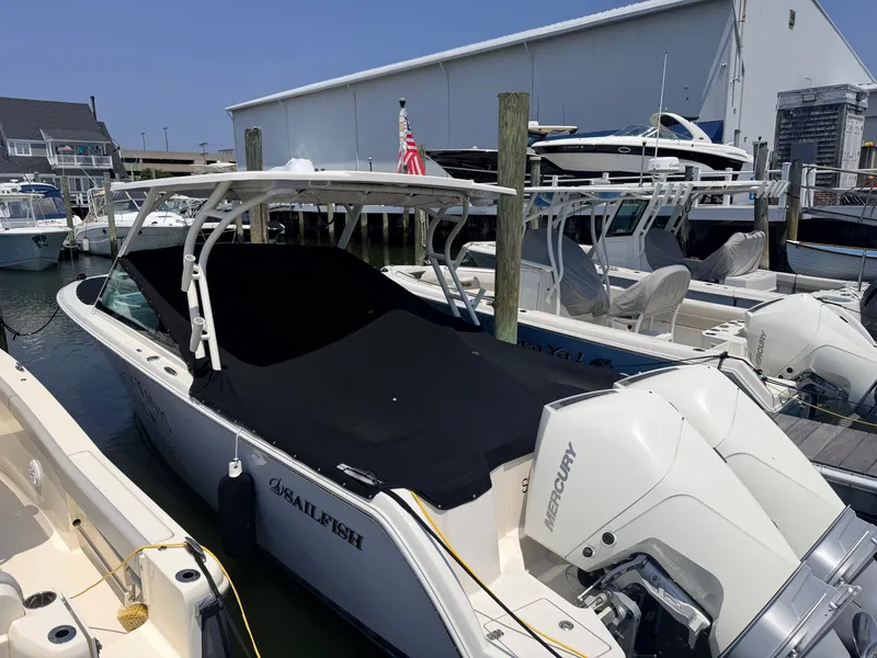 Slide: The Image of A 2022 Sailfish 276 DC docked at a marina. It features a black cover and a Mercury engine. - 23