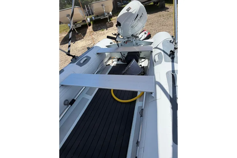 Slide: The Image of 2022 Achilles inflatable boat with Suzuki outboard motor, docked on gravel. - 4