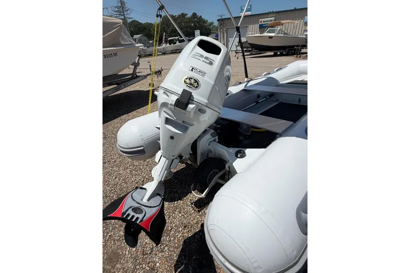 Slide: The Image of 2022 Achilles inflatable boat with outboard motor, displayed outdoors on gravel surface. - 9