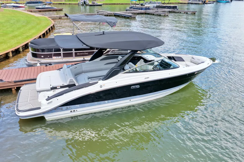 Slide: The Image of 2025 Sea Ray SLX 280 boat docked on a serene lake with lush surroundings. - 1