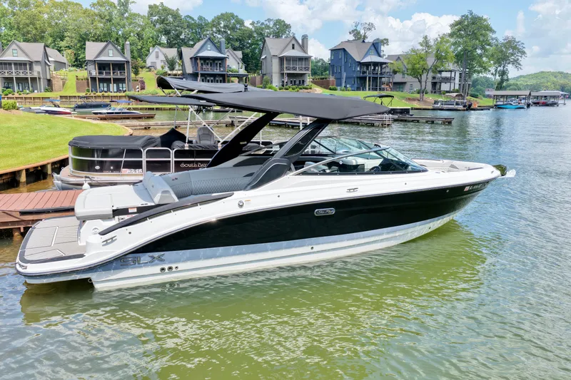Slide: The Image of 2025 Sea Ray SLX 280 boat docked on a scenic lake with waterfront homes. - 3
