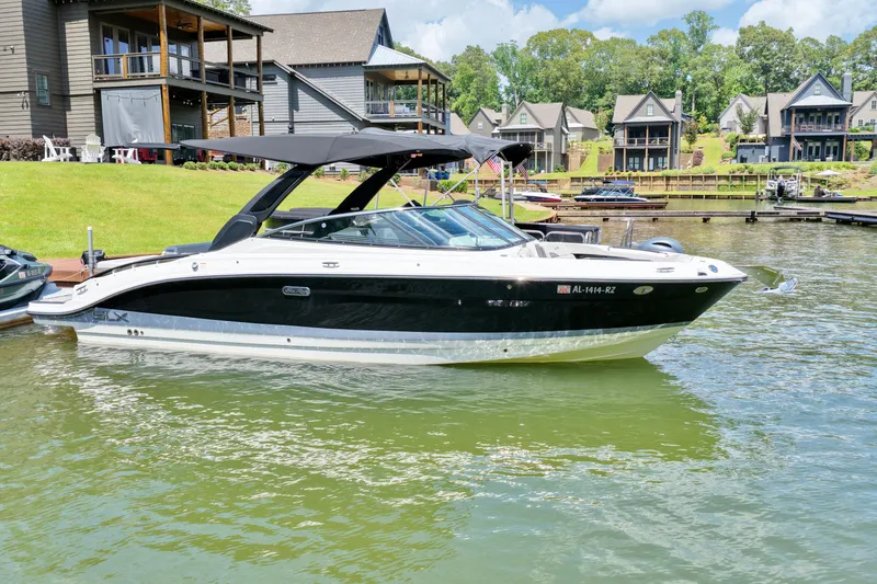 The Image of 2025 Sea Ray SLX 280 boat docked on a serene lake with houses in the background. - 0