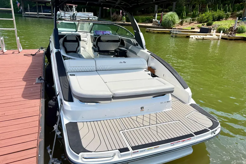 Slide: The Image of 2025 Sea Ray SLX 280 boat docked on a serene lake with luxurious seating. - 7