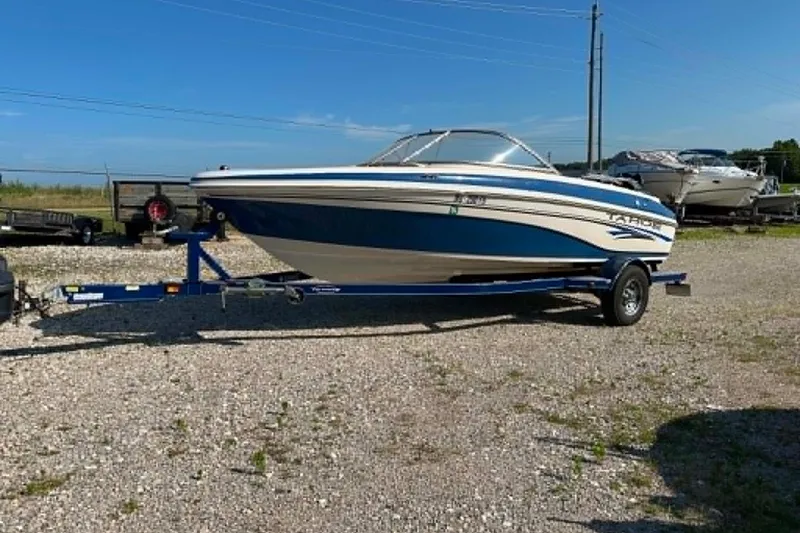 The Image of 2006 Tahoe Q6 Sport boat on trailer, parked on gravel lot under clear blue sky. - 0