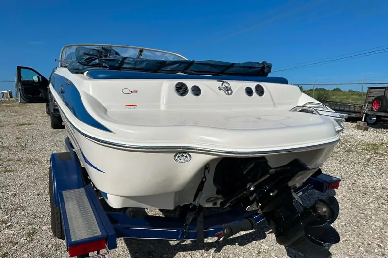Slide: The Image of 2006 Tahoe Q6 Sport boat on trailer, rear view, parked on gravel under clear blue sky. - 5
