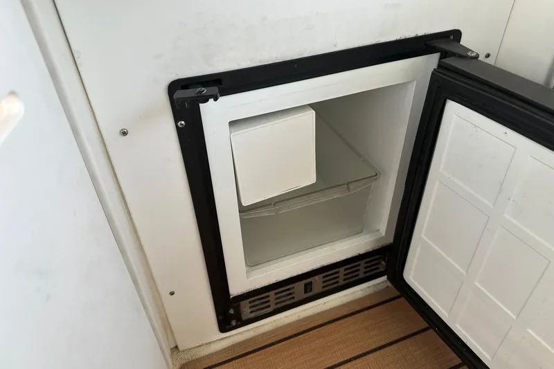 Slide: The Image of Open mini fridge on 2001 Sea Ray 410 Sundancer boat, showing interior storage space. - 9